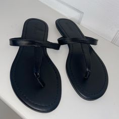 Brand New Without Tags Black T-strap Sandals For Summer, Black Round Toe T-strap Sandals For Summer, Black Single Toe Strap Flip Flops For Vacation, Black Single Toe Strap Sandals For Summer, Black Single Toe Strap Summer Sandals, Casual Black Synthetic T-strap Sandals, Black T-strap Sandals With Cushioned Footbed For Vacation, Casual Black Flip Flops With Single Toe Strap, Black T-strap Toe Post Sandals For Vacation