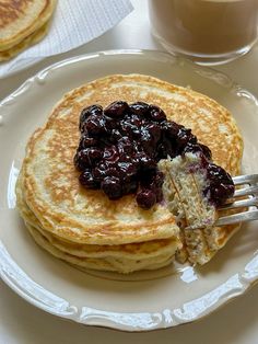 pancakes with raisins and butter on a plate next to a cup of coffee