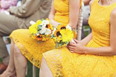 two women in yellow dresses are sitting on chairs with sunflowers and other flowers