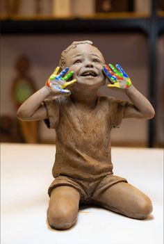 a statue of a boy holding two hands up to his face