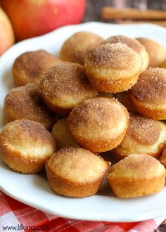 a white plate filled with sugared donuts on top of a red and white checkered table cloth