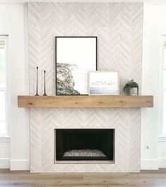 a fireplace with white chevron tile and wood mantle