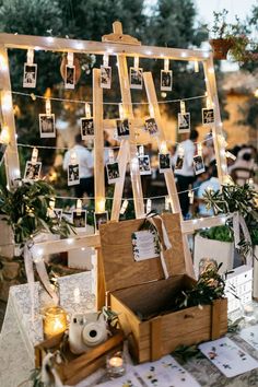 an easel with pictures hanging from it and candles on the table next to it