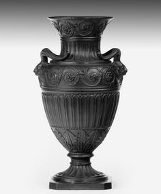 an ornate black vase is shown on a white background