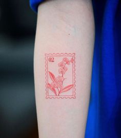 a red stamp with flowers on it and the number twenty is in front of someone's arm