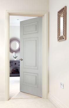 an open door in a white room with a mirror on the wall and carpeted floor