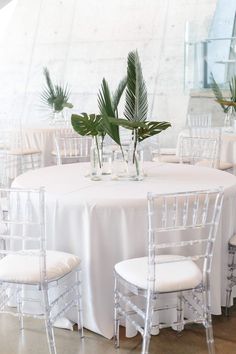 there are many chairs around the table with plants in vases on top of them