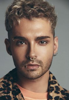 a close up of a person wearing an animal print shirt and piercing on his nose