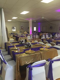 the banquet room is set up with gold and purple linens, white chairs, and blue sashes