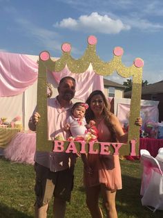 a man and woman holding a baby in front of a princess sign