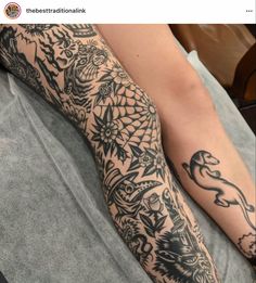 a person laying on top of a bed with tattoos on their arm and leg sleeves