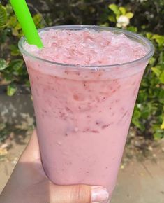 a person holding up a pink drink with a green straw in it's hand