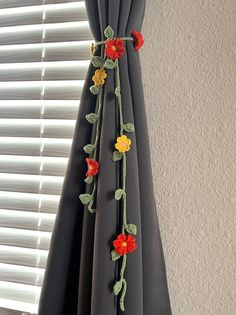 a curtain with crocheted flowers hanging from it's side in front of a window