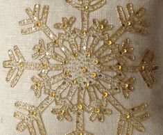 a white pillow with gold sequins and snowflakes on it's side