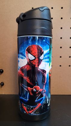 a spider man travel mug sitting on top of a table