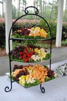 three tiered trays filled with different types of fruits and vegetables on a table