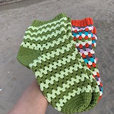 a person holding three crocheted items in their hands on the beach, with sand and water behind them