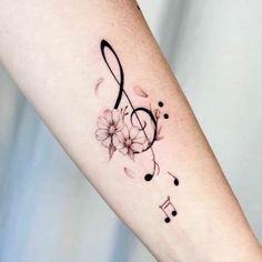 a tattoo with musical notes and flowers on the arm