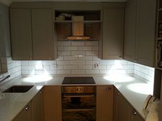 an empty kitchen with white counter tops and light on the stove top, oven door open