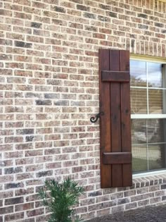 an open window on the side of a brick building next to a potted plant