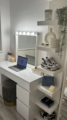 a laptop computer sitting on top of a white desk next to a shelf filled with shoes