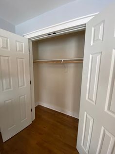 an empty closet with white walls and wooden floors