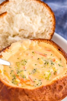 a close up of a bowl of soup on a plate with bread in the background