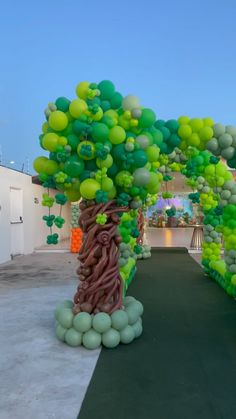 an arch made out of balloons with trees on the sides and green leaves on the top