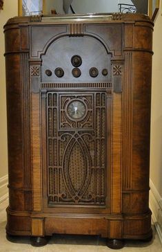 an old fashioned wooden cabinet with a clock on it's front and side panels