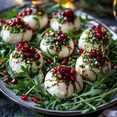 small appetizers are arranged on a plate with greens and pomegranates