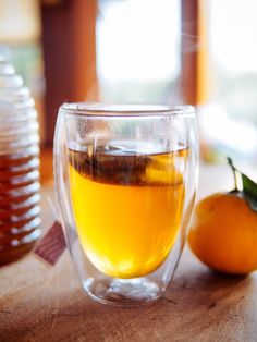 a cup of tea next to an orange on a table