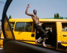 a man standing in front of a yellow van with his hand up to the side