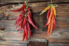 red and yellow peppers hanging from strings on wooden planks