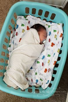 a baby is sleeping in a basket on the floor