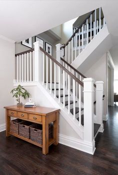 a wooden table sitting under a stair case next to a white bannister on top of a hard wood floor