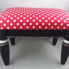 a polka dot bench with black legs and white dots on red fabric, sitting against a gray background