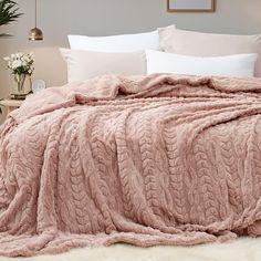 a bed covered in a pink blanket and pillows