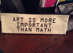 an art is more important than math written on a canvas zippered pouch sitting on a desk