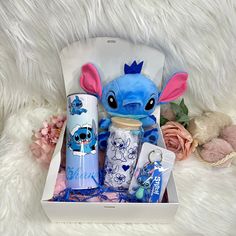 a blue stuffed animal sitting inside of a white box next to some other items and flowers