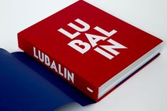 a red book sitting on top of a white table next to a blue object with the word lu bak in it