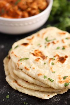 several flat breads stacked on top of each other next to a bowl of chickpeas