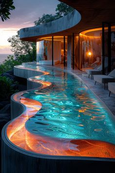 an outdoor swimming pool with lights reflecting off the water at sunset or dusk, in front of a house