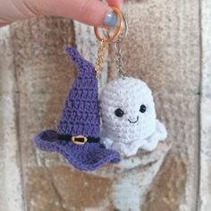 a hand holding a keychain that has two small items on it, one is white and the other is purple