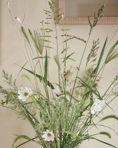 a vase filled with lots of white flowers and greenery on top of a table