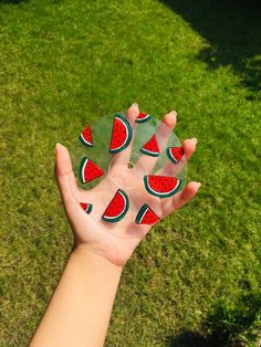 a hand holding a piece of glass with watermelon slices on it