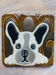 a ceramic tile with a dog's face in the center on a wooden surface