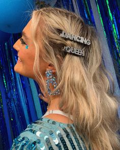 a woman with two hair clips on her head in front of blue and green balloons