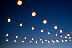 string lights are hanging from the ceiling in front of a blue sky at night time