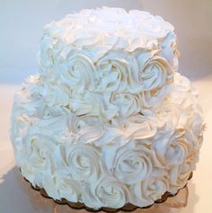 a three tiered cake with white frosting roses on it's sides and bottom