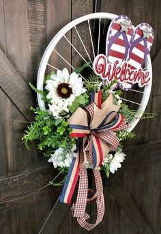 a welcome wreath hanging on the side of a wooden door with flowers and flip flops